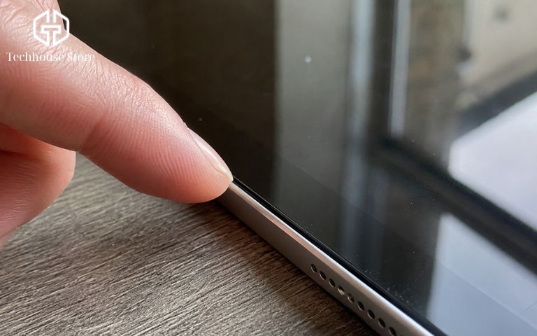 Có nên mua iPad cũ không? Kinh nghiệm mua máy ngon, tiết kiệm và an toàn Cận cảnh ngón tay người dùng đang vuốt dọc theo viền tiếp xúc giữa màn hình và vỏ kim loại của iPad để tìm dấu vết tháo mở.