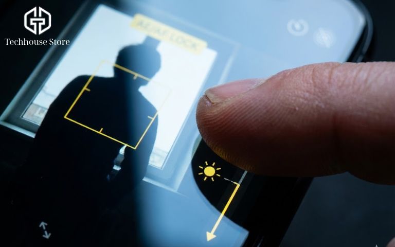 10+ Mẹo Chụp Ảnh Đẹp Bằng iPhone: Ai Cũng Làm Được (Từ Cơ Bản Đến Pro) Ngón tay người dùng đang chạm vào màn hình iPhone và kéo biểu tượng mặt trời để chỉnh độ sáng.