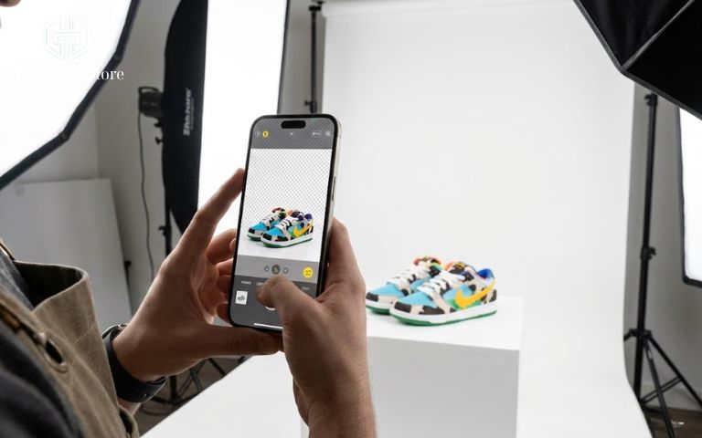 Top 15+ App Chụp Ảnh Đẹp Trên iPhone Miễn Phí 2026 Chủ shop online đang chụp ảnh giày thể thao bằng iPhone với phông nền studio tối giản.