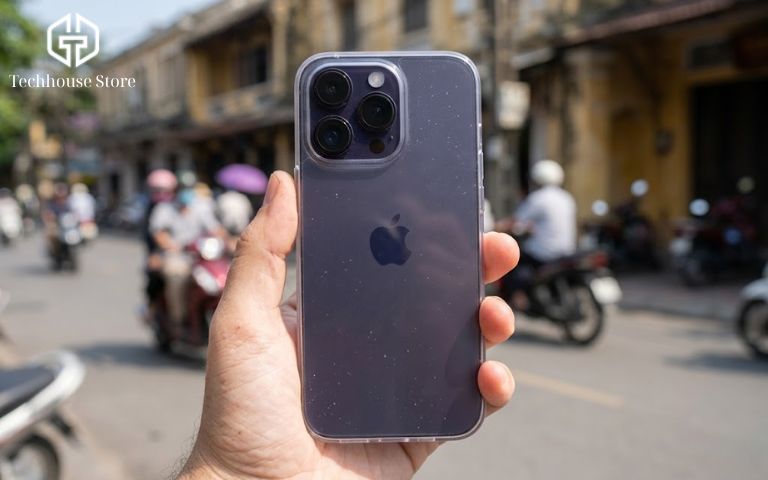 Cận cảnh cụm 3 camera lồi và mặt lưng kính nhám của chiếc iPhone 14 Pro màu tím đậm được cầm gọn gàng trong lòng bàn tay.