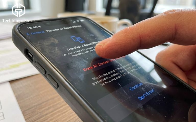 Cận cảnh ngón tay thao tác chọn mục Xóa tất cả nội dung và cài đặt trên iPhone để kiểm tra máy dính iCloud.