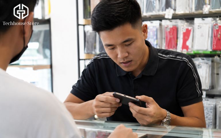 Dùng sạc nhanh cho iPhone có hại pin không? Cách sạc an toàn, bền pin hơn Kỹ thuật viên tại cửa hàng đang cầm điện thoại trên tay để kiểm tra kỹ lưỡng cổng sạc và tình trạng pin trước khi giao cho khách.