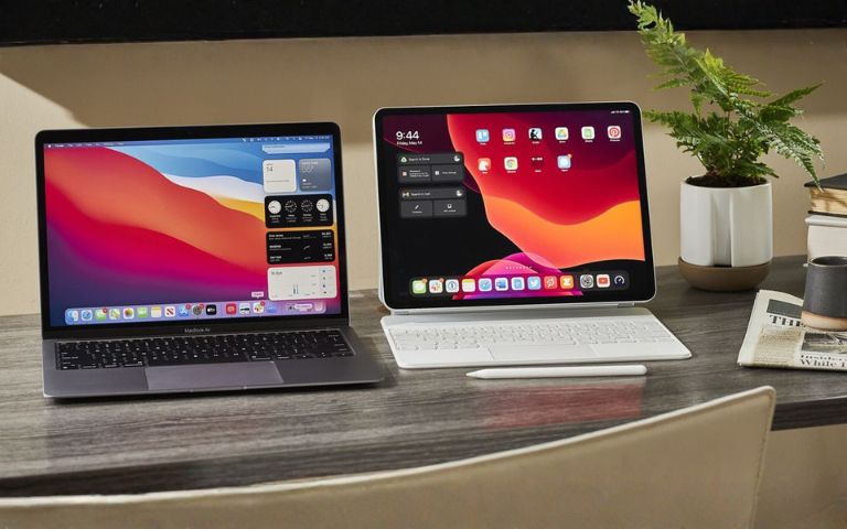 Nên mua MacBook Air hay iPad Pro? Máy chính hay thiết bị linh hoạt mới hợp với bạn? So sánh MacBook Air và iPad Pro được đặt cạnh nhau trên bàn làm việc.