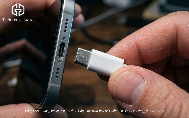 Cận cảnh một tay đang cầm đầu cáp sạc USB-C chuẩn bị cắm vào cổng sạc ở cạnh dưới của một chiếc điện thoại thông minh viền kim loại.