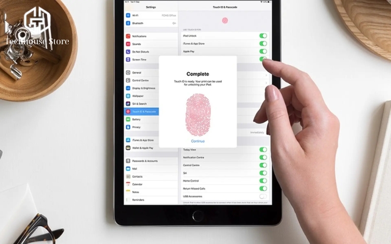 So sánh iPad Air 4 và iPad Gen 9: đâu là lựa chọn phù hợp với bạn? Cận cảnh bàn tay khách hàng đang nhấn ngón trỏ vào nút nguồn trên cạnh trên của chiếc iPad Air 4 cũ để kiểm tra Touch ID tại cửa hàng.