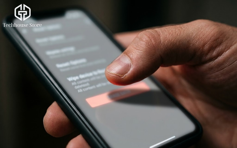 Bán iPhone cần làm gì? Các bước cần nhớ trước khi giao máy Cận cảnh ngón tay cái đang chuẩn bị chạm vào một nút bấm cảnh báo màu đỏ ở cuối màn hình cài đặt của điện thoại di động.