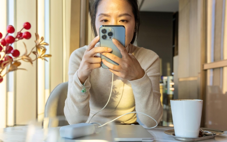 Cách bảo vệ pin iPhone giúp pin bền hơn khi sử dụng Người dùng sử dụng iPhone đang cắm sạc trong sinh hoạt hằng ngày.