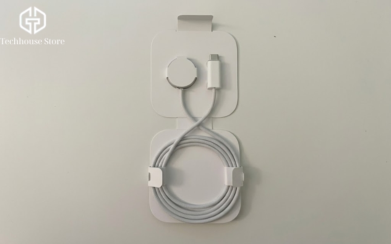 Cách sạc Apple Watch đúng cách cho người mới sử dụng Dây sạc từ tính Apple Watch màu trắng với đầu cắm USB-C và đầu sạc tròn, được cuộn gọn trong khay đựng.