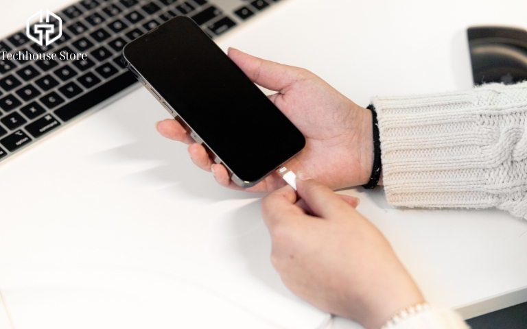 Người dùng cắm cáp sạc vào iPhone để kiểm tra tình trạng loạn cảm ứng liên quan đến phụ kiện sạc.