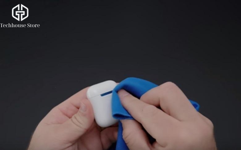 Cách vệ sinh tai nghe AirPods và hộp sạc tại nhà đúng cách cho từng đời Lau vỏ hộp sạc AirPods bằng khăn mềm màu xanh.